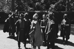 Historical black and white photograph of a group gathered outdoors in vintage clothing.