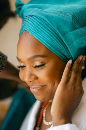 Close-up shot of turquoise headwrap being adjusted during preparation.