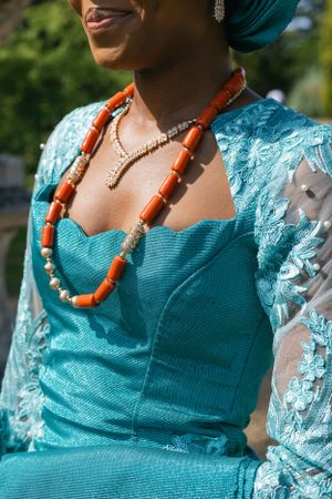 Traditional turquoise dress with orange coral beaded necklace and lace sleeves.