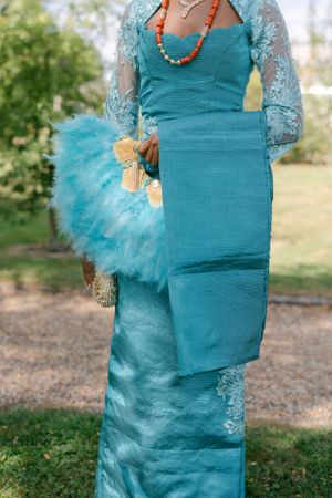 Elegant turquoise gown with lace sleeves and matching tulle handbag accessory.