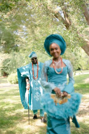 Artistic wedding photo through tree branches showing couple in matching turquoise traditional attire.