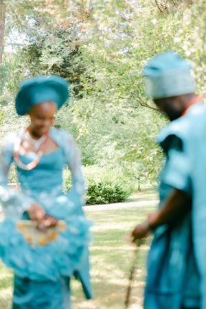 Soft focus artistic shot of couple in traditional blue African attire standing in a garden.