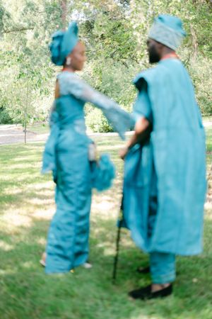 Blurred artistic photo of couple in blue traditional attire dancing in a garden setting.