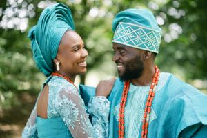Couple in matching turquoise traditional African wedding attire sharing an intimate moment.