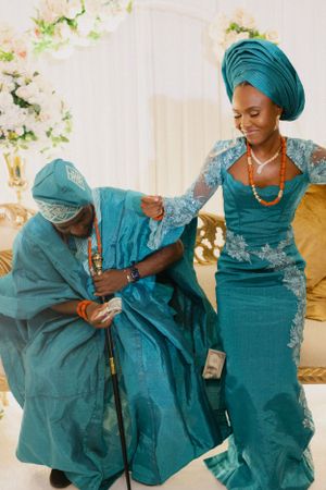 Two people in coordinated teal traditional outfits sharing playful interaction.