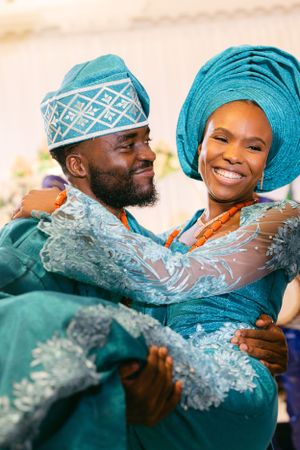 Couple in matching teal traditional attire sharing intimate moment at celebration.