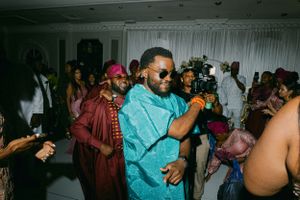 Dance party scene with guests in traditional African attire dancing under indoor lighting.