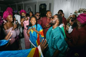 A lively celebration features attendees in vibrant African garments dancing and taking photos.