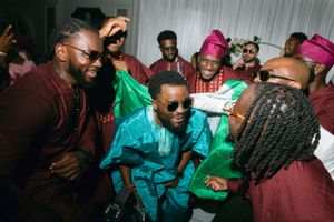 Partygoers wearing bright traditional African clothing dance together at a festive celebration.