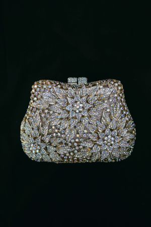Crystal-encrusted evening clutch with intricate floral patterns on black background.