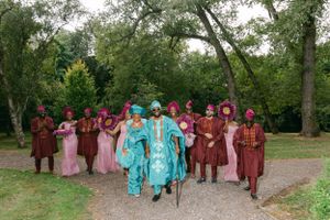 Wedding party in colorful burgundy and turquoise attire poses together on a garden path.