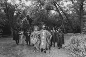 Black and white photo of a wedding procession walking through a garden landscape.