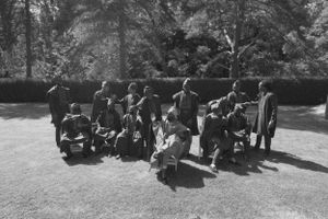 Black and white vintage photo of a seated group gathered outdoors in formal attire.