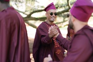 People in burgundy robes and magenta caps share a celebratory moment outdoors.