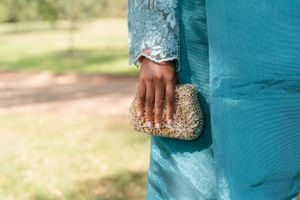 Detailed shot of sparkly gold clutch purse held against turquoise fabric.