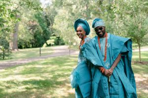 Couple in matching turquoise traditional outfits sharing a joyful moment in a park.