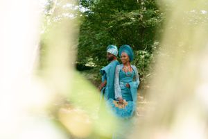Dreamy filtered photo of figures in turquoise attire through garden foliage.