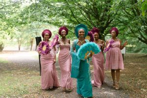 Wedding party in pink and turquoise traditional Nigerian attire walking through a park.