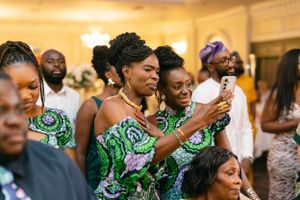 Attendees in matching green patterned outfits dance and celebrate at a formal gathering.