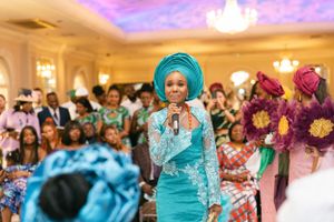 Traditional celebration in an elegant ballroom with colorful attire and floral decorations.