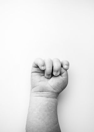 Black and white photograph of a clenched fist against a white background showing determination and defiance.