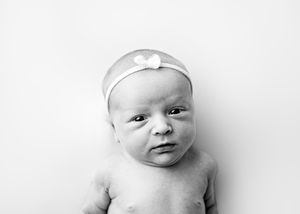 A series of four black and white photos show a baby in different playful poses against a white backdrop.