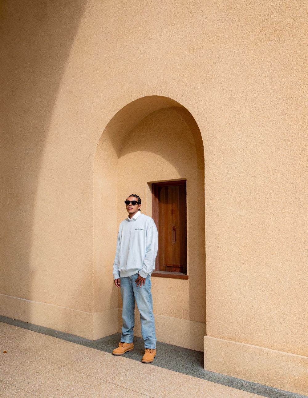 A progressive sequence showing someone moving down a covered walkway with arched passages and peach colored walls.
