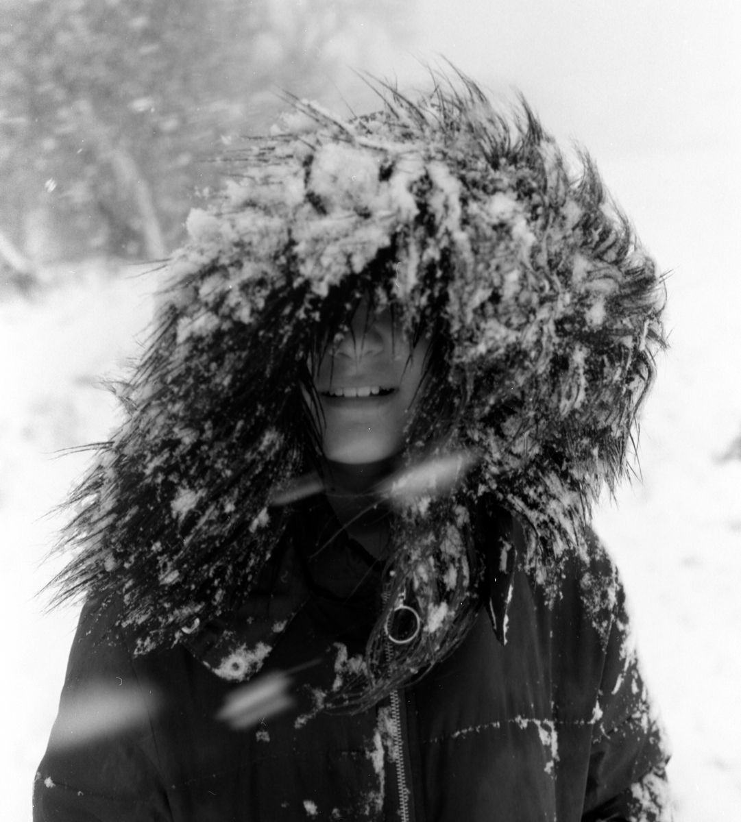 Child in the snow covered with a coat