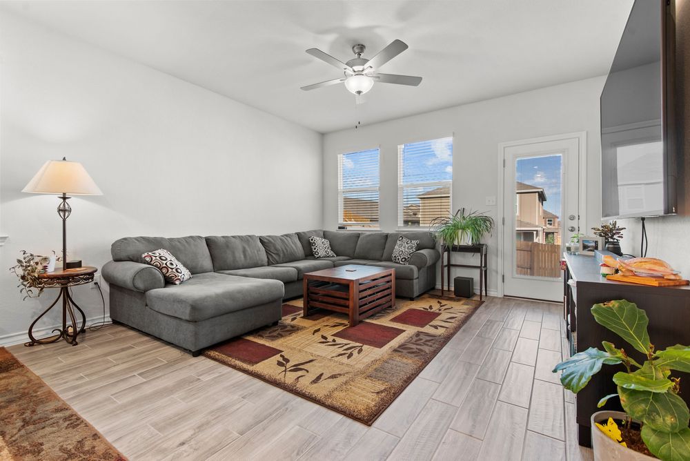 Modern living room features light gray walls, white ceiling fan, plush sectional and large area rug.