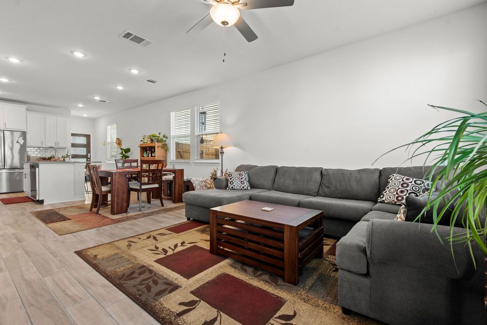 Contemporary living room with grey sectional, wood coffee table, and open floor plan connecting to dining area.