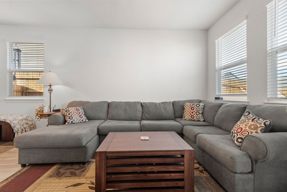 Modern living room with gray sectional sofa, wooden coffee table, and decorative accent pillows in neutral tones.