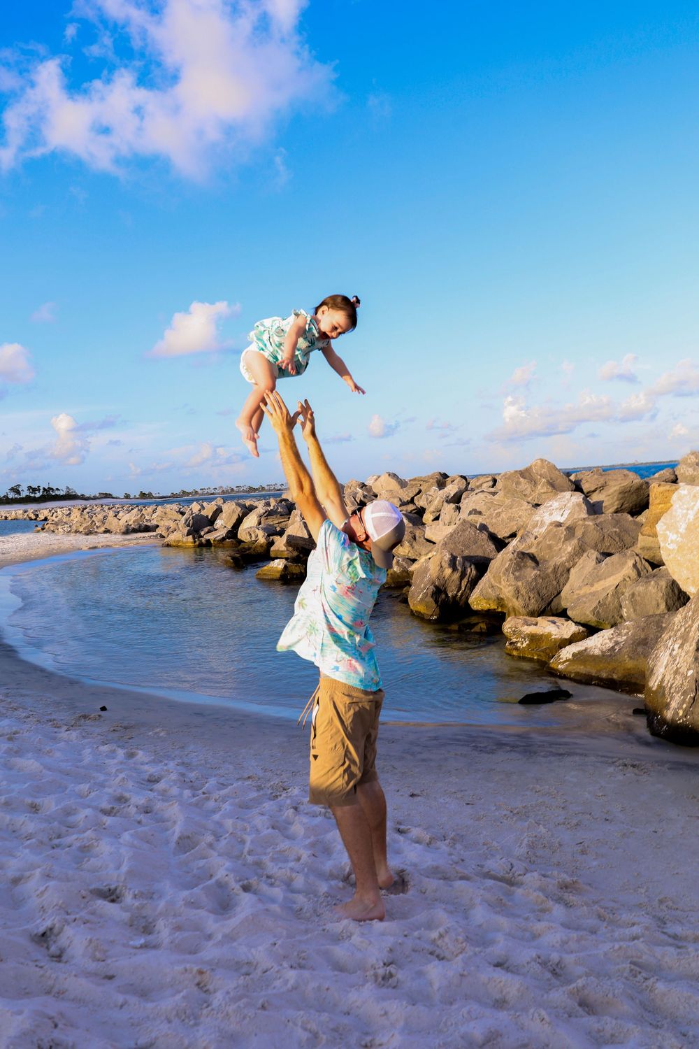 A sequence of photos showing someone doing a backflip on a rocky beach with blue sky and ocean in the background.