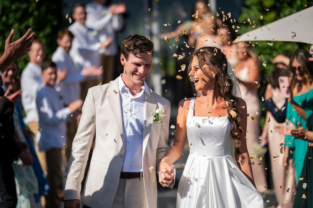 Newlyweds exit their ceremony while guests celebrate with confetti.