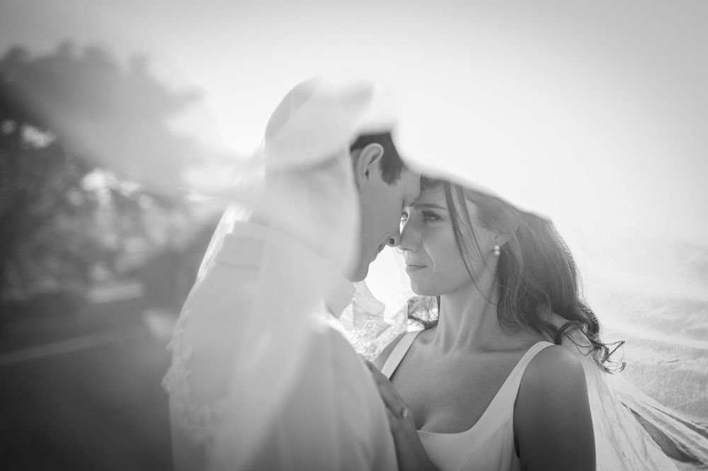 A black and white wedding photo capturing a tender moment between a couple during sunset.