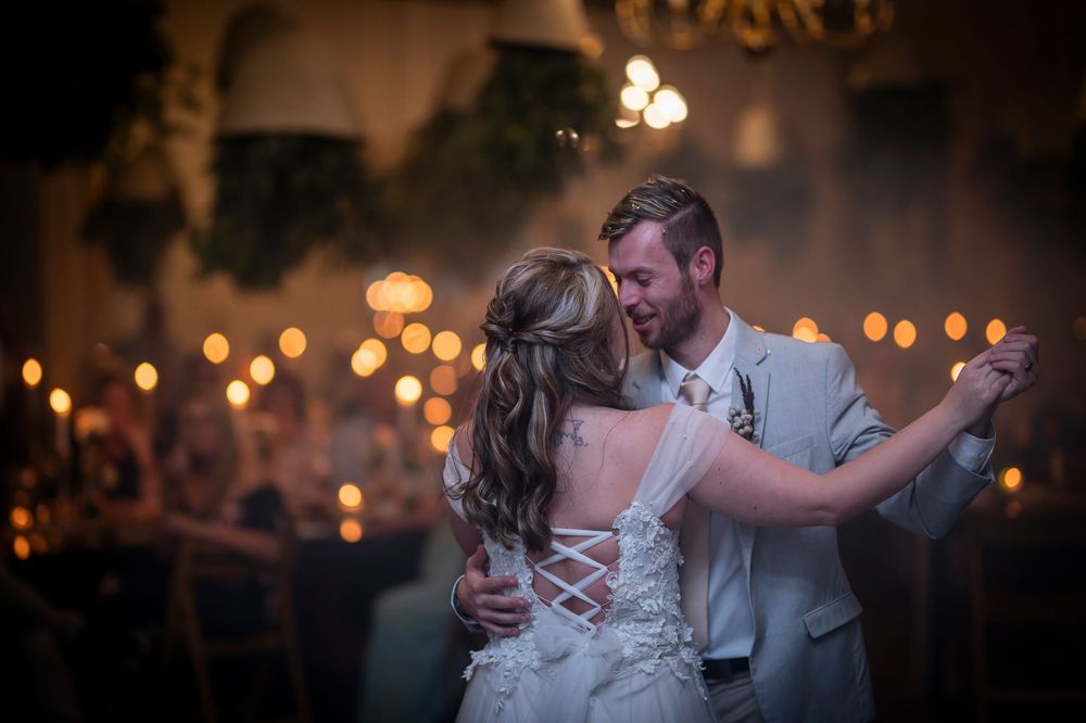 A couple shares their first dance at their wedding reception with warm bokeh lights in background.