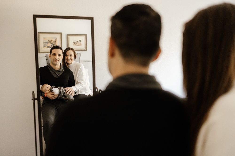 Bay Area newborn photography capturing parents smiling at their mirror reflection in Los Gatos
