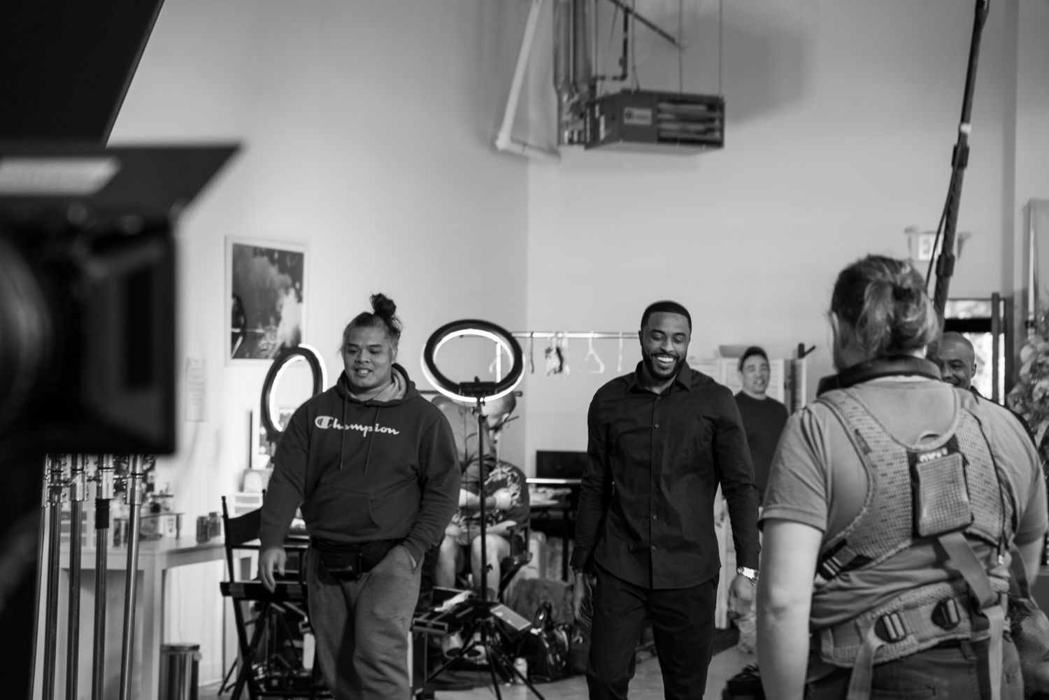 Behind-the-scenes photo of a film or video production crew working with camera equipment and lights in monochrome.