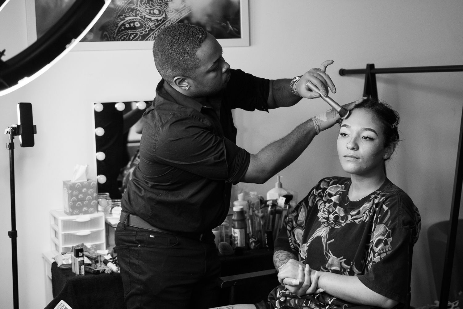 Black and white photo of a hairstylist working with a client in a salon setting.