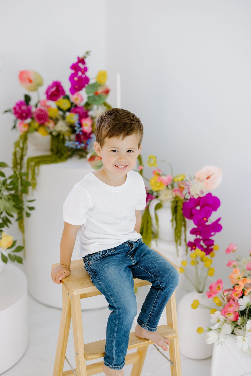 White background portrait with colorful floral arrangements featuring bright pink orchids and soft peach blooms.