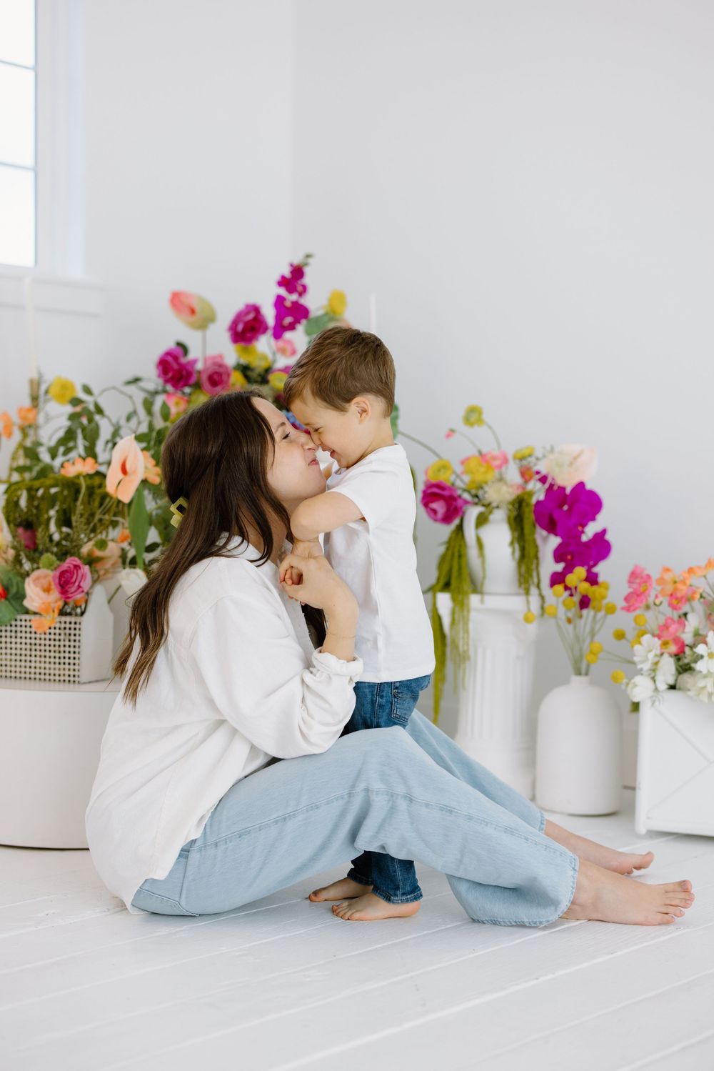 A tender moment shared between parent and child against a backdrop of colorful spring flowers in white vases.