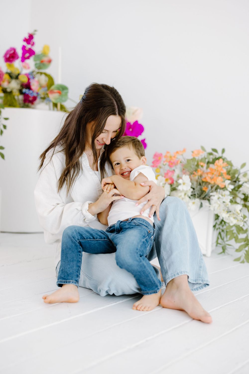 A loving moment between parent and child on a white floor with colorful flowers in the background.