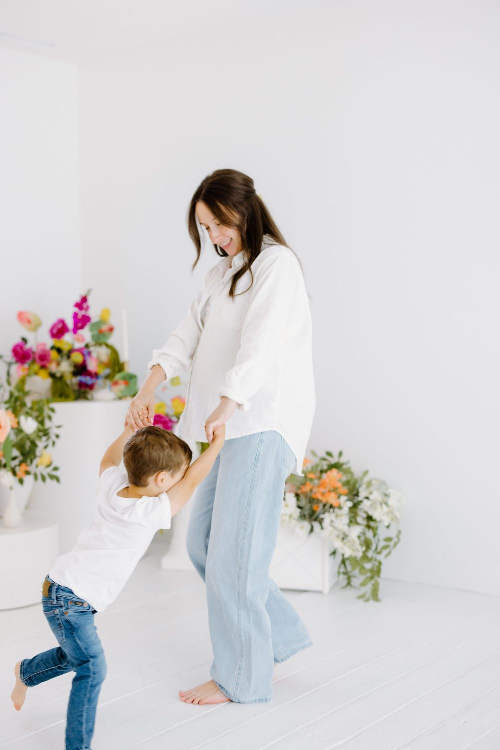 A playful dance moment in a bright white room with colorful floral arrangements adding a cheerful touch to the scene.