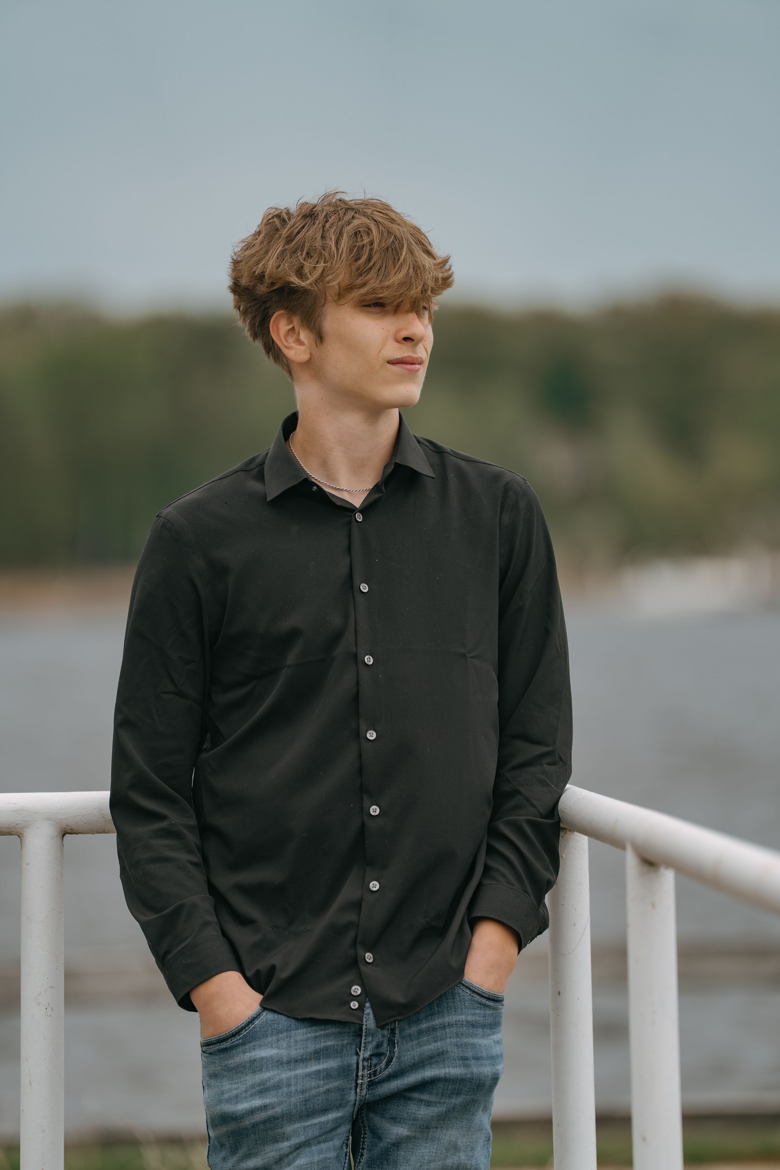 Casual portrait of someone wearing a dark button-down shirt against a lakeside background.