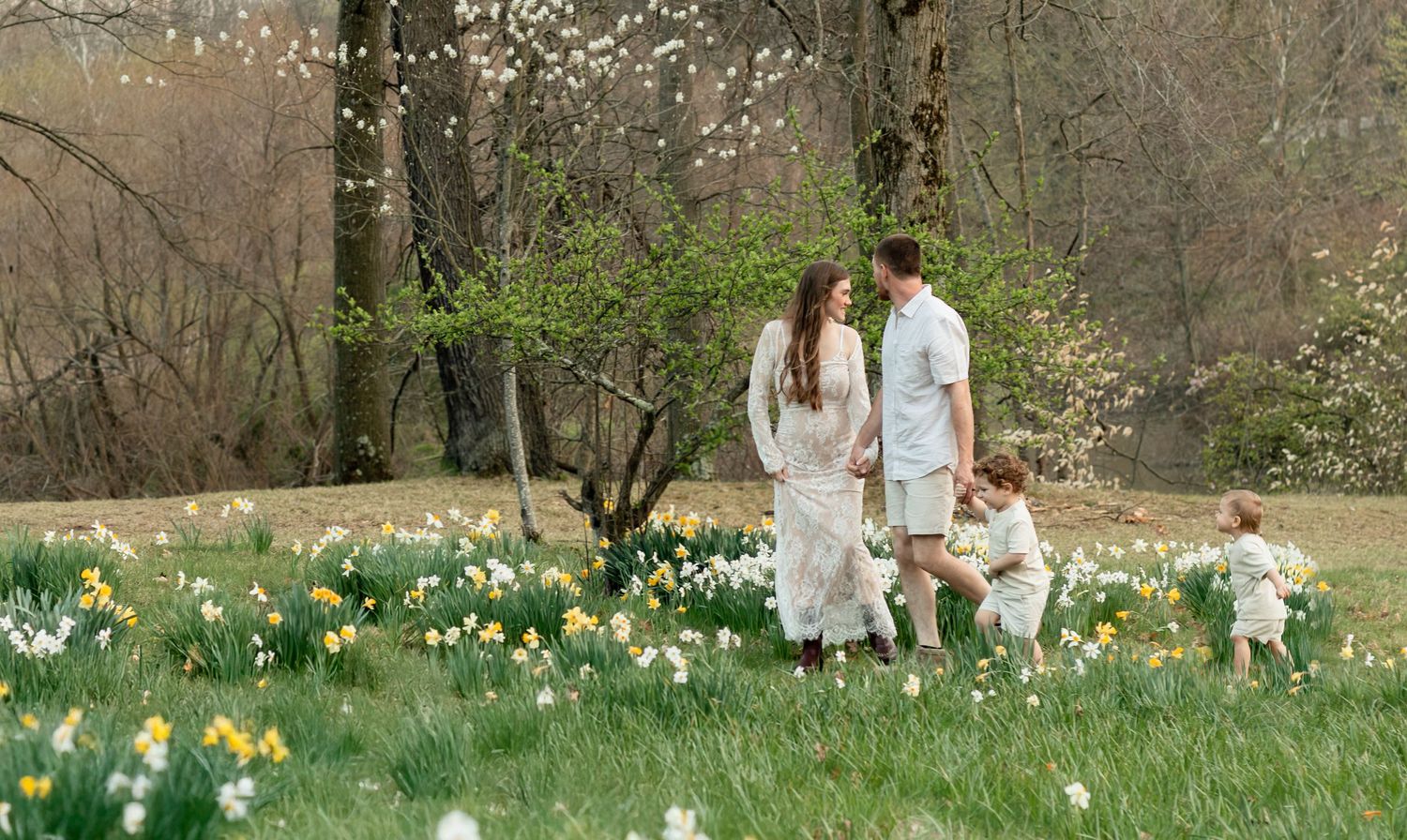 A spring garden scene with blooming daffodils and tulips where a family shares a sweet moment outdoors by a lake.