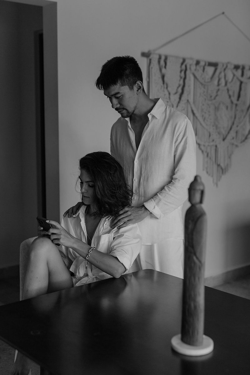 A romantic black and white photo of a couple in white shirts sitting at a table with a candle, creating an intimate atmosphere.