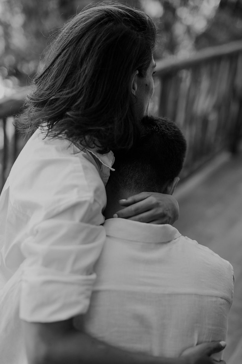 Intimate black and white photo showing tender embrace of two people in white shirts from behind.