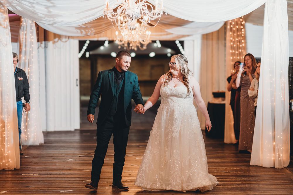 Romantic first dance moment under draped fabric and warm lighting at an indoor wedding reception.