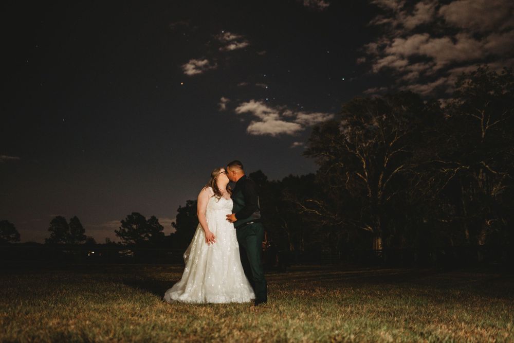 Silhouette of a couple in wedding attire embracing under a starlit night sky.