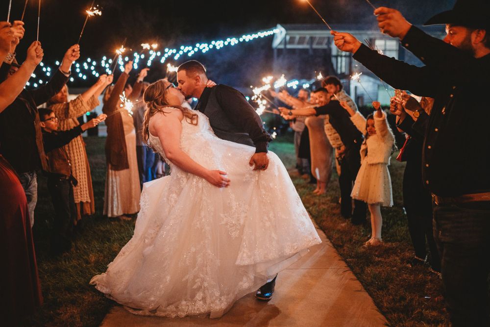 Wedding couple dancing surrounded by guests holding sparklers during nighttime celebration.