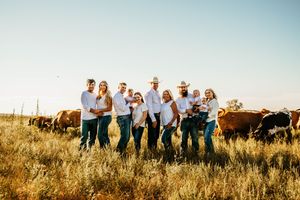 A group of people stand together in a field at sunset creating a panoramic view across multiple photos.